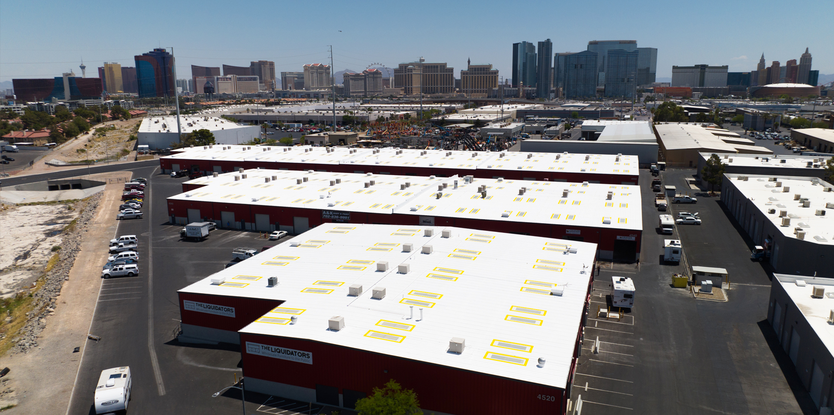 Aerial view of several large industrial warehouses with white rooftops labeled "Solo Cup Co." in a busy urban area with high-rise buildings in the background.