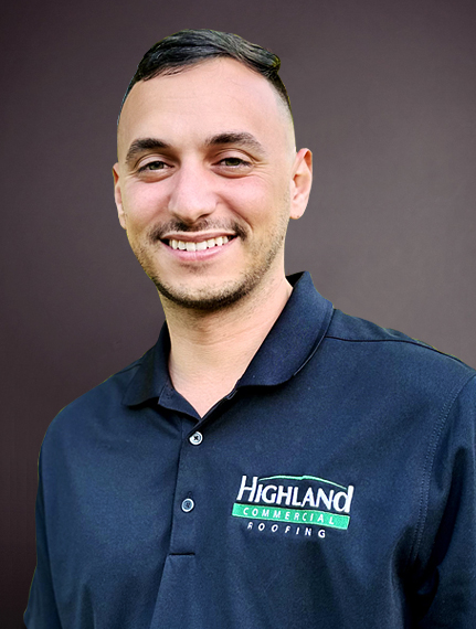 A man in a black polo shirt with the "Highland Commercial Roofing" logo stands in front of a plain dark background, smiling at the camera.